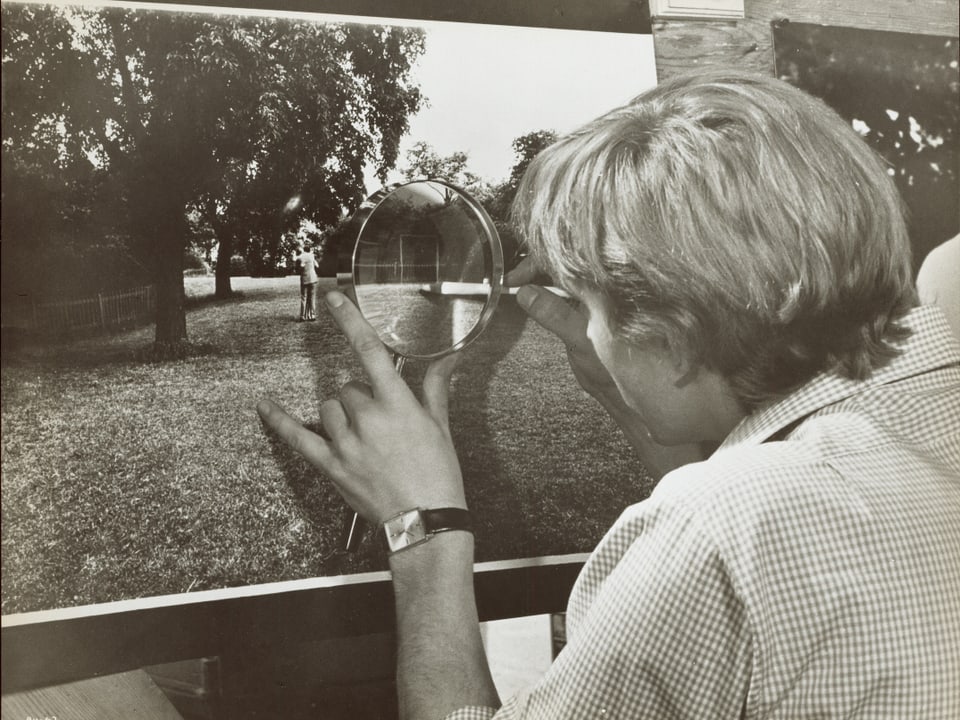 David Hemming schaut eine Fotografie durch eine Lupe an.