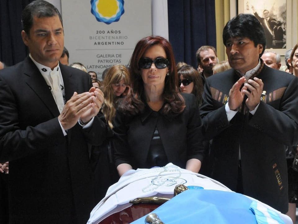 Cristina am Grab ihres Mannes, begleitet von Morales (rechts) und Correa (links).
