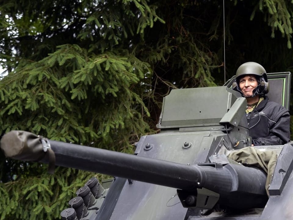 Doris Leuthard mit Helm und Armeejacke auf einem Panzer
