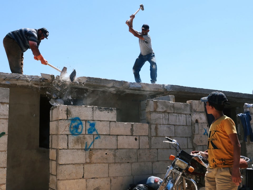 Arbeiter zerstören eine Betonmauer