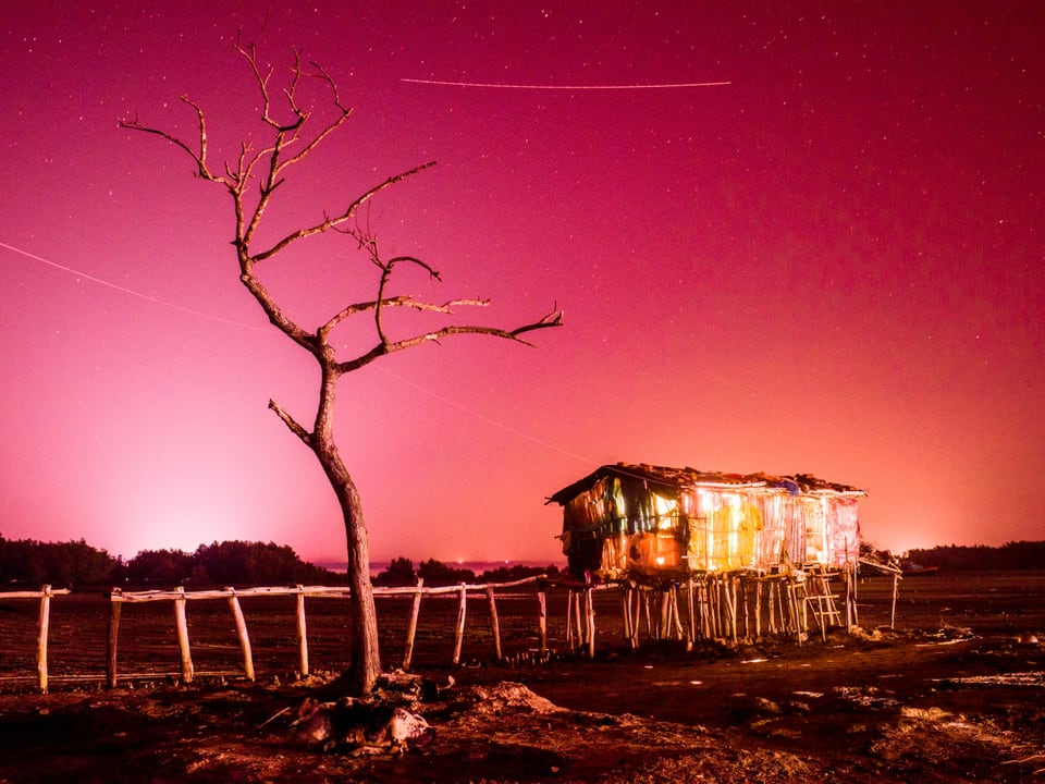 Fotografie einer Hütte in der Wüste, die rot leuchtet.