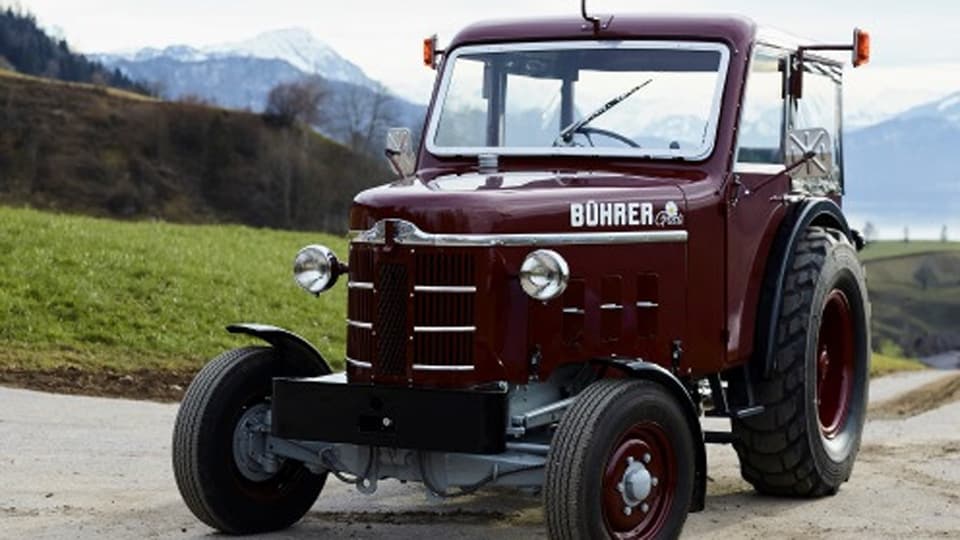 Alter weinroter Traktor der Marke Bührer steht auf einem Feldweg. 