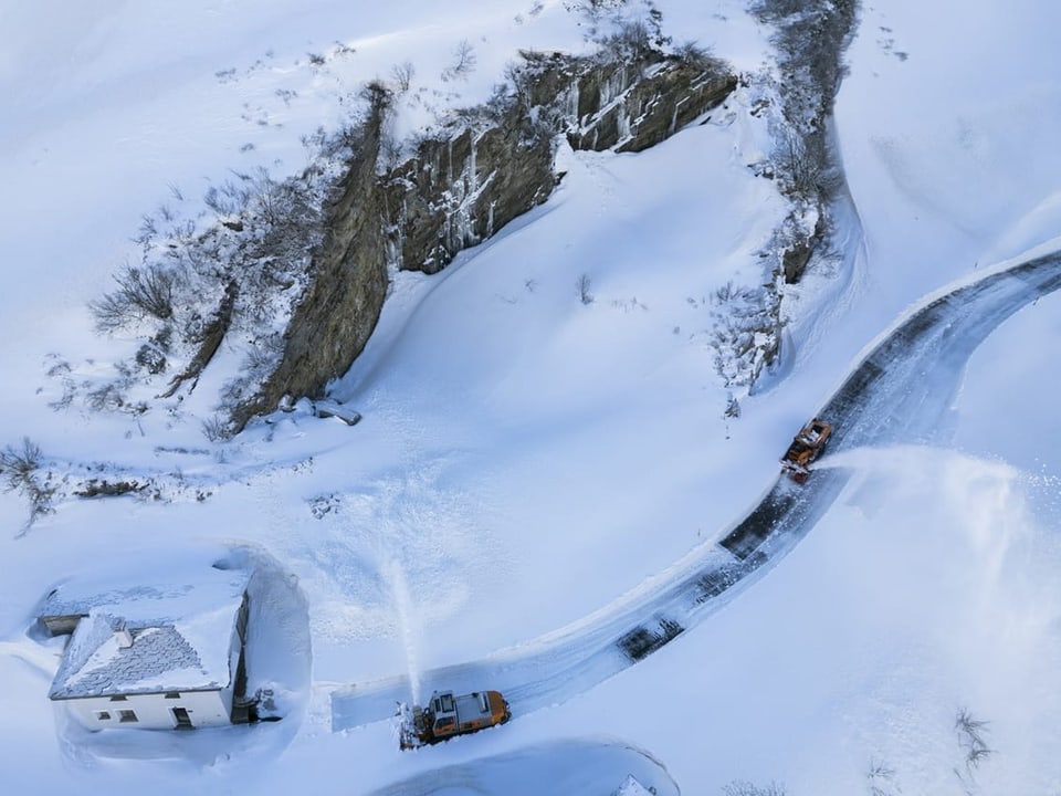 Eine Schneelandschaft mit einer Strasse von oben fotografiert. 
