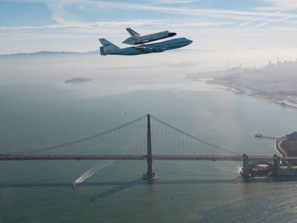 Eine 747 transportiert ein Space Shuttle über die Golden Gate Bridge.