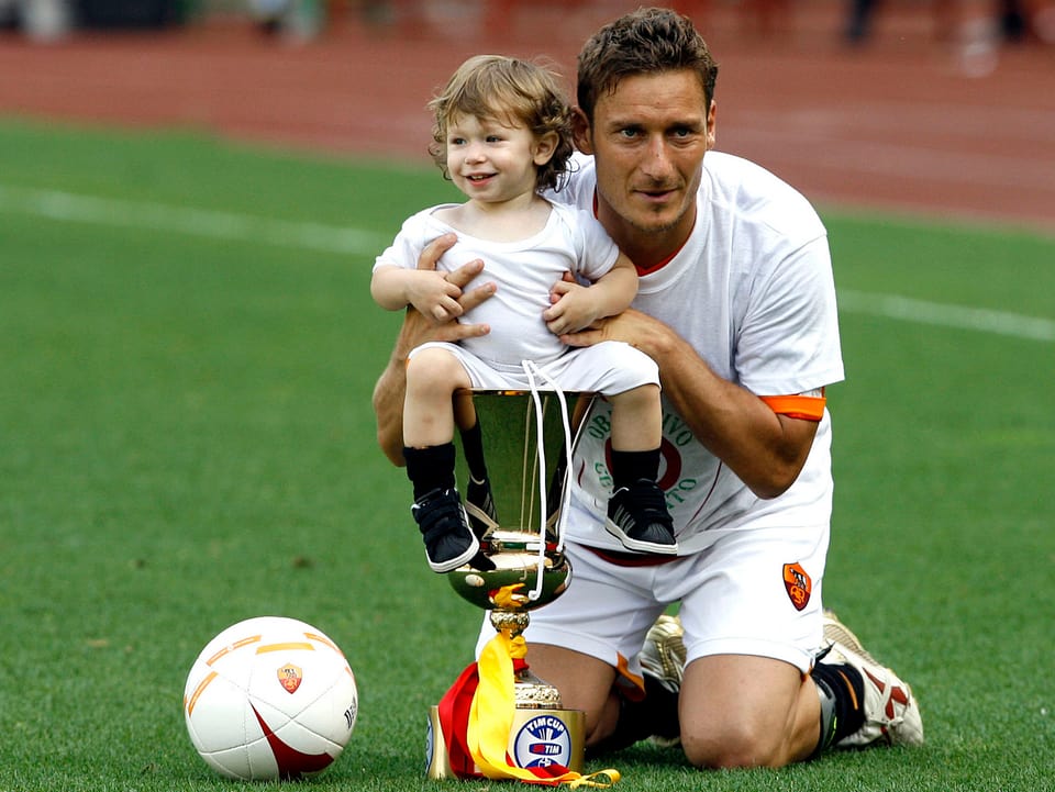 Francesco Totti und sein Sohn posieren mit einem Pokal.