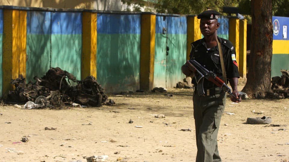 Afrikanischer Polizist in Kano vor Trümmern eines Anschlags.