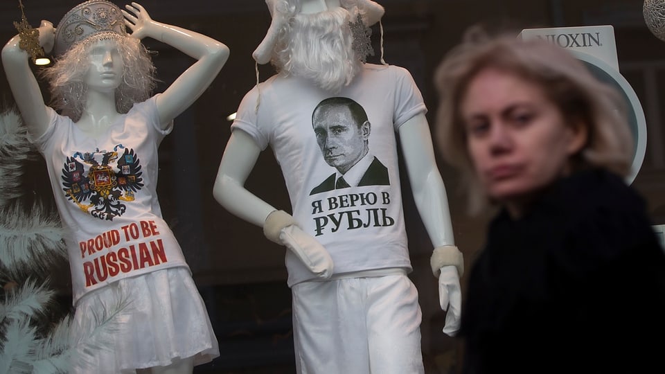 Frau vor einem Schaufenster, zwei Schaufensterpuppen mit «proud to be russian»-Shirts.