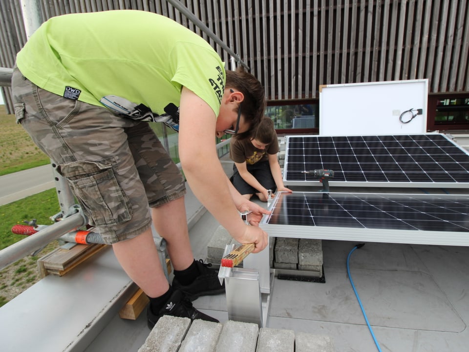 Jugendliche messen ein Solarpanel aus und schauen, ob es passend installiert werden kann.