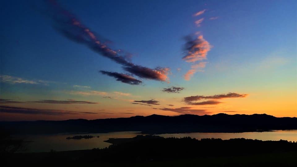 Blick vom Etzel zum Seedamm, darüber ein tiefblauer Himmel und dahinter ein zartes Morgenrot über dem Zürcher Oberland.