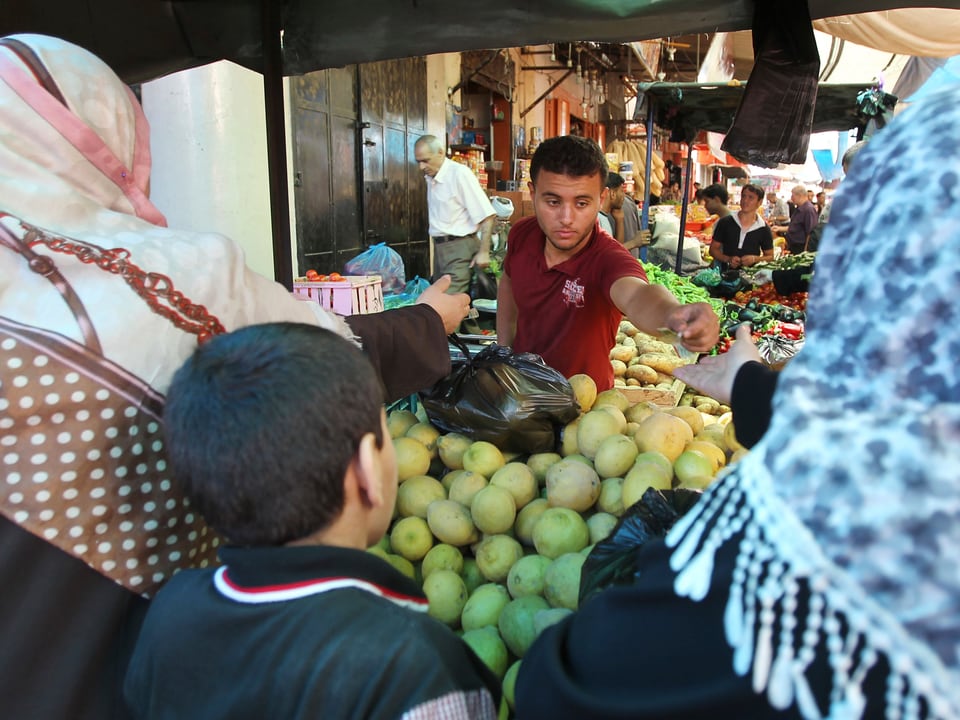 Frauen und Kinder kaufen auf dem Markt von Gaza Stadt Früchte und Süssigkeiten. 