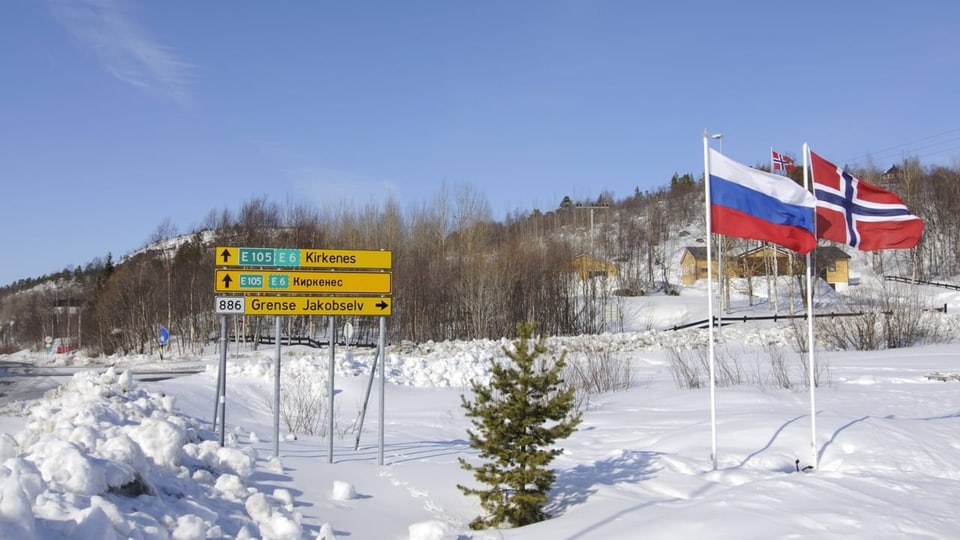 Zweisprachige Strassenschilder und die Flaggen von Russland und Schweden.