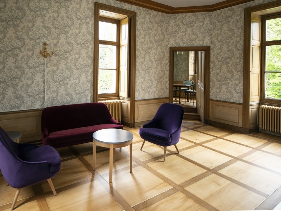 Ein Schlafzimmer im renovierten Schloss Schaudau: Eichenböden und moderne violette Sessel. 