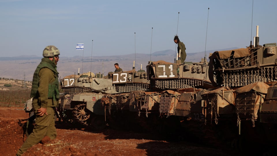 Vier israelische Panzer; darauf und daneben sind drei Soldatinnen und Soldaten zu sehen