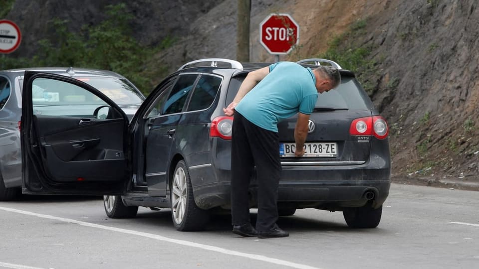 Ein Mann überklebt das Länderkennzeichen seines Autos