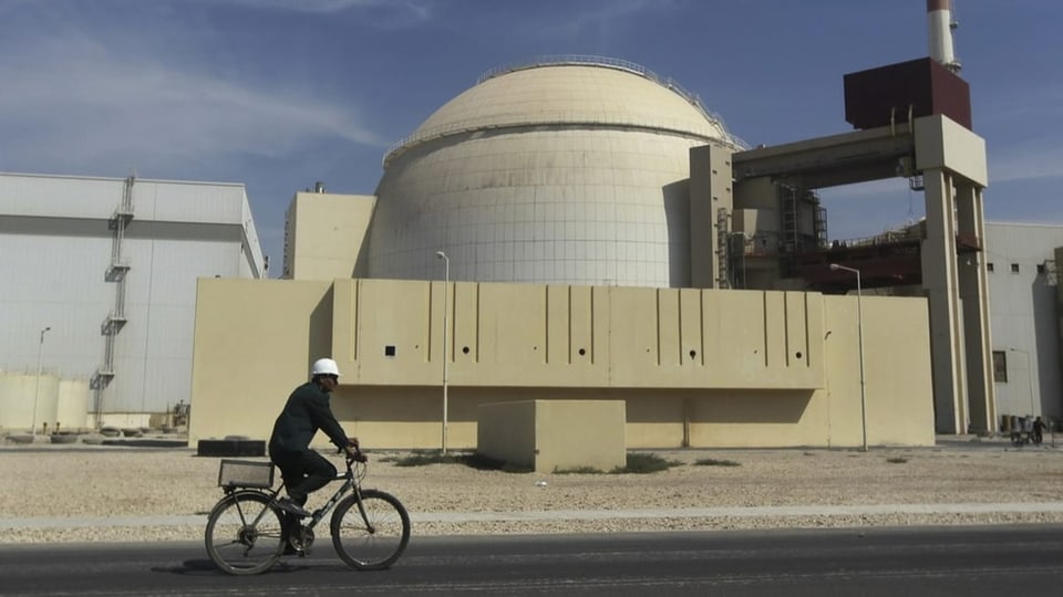 Arbeiter fährt mit dem Fahrrad an einem Reaktorgebäude eines Kernkraftwerks im Iran vorbei.