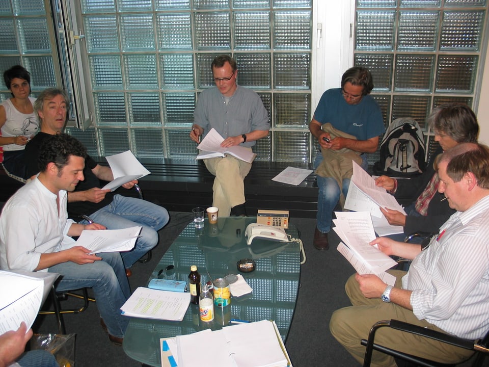 Schauspieler und Regie sitzt zusammen und lesen gemeinsam das Drehbuch durch.
