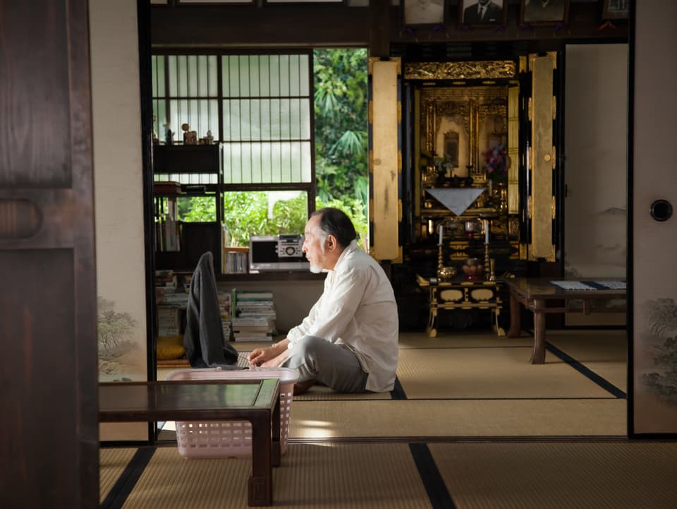 Schauspieler Isao Hashizume sitzt auf Tatami-Matten in seinem Wohnzimmer.