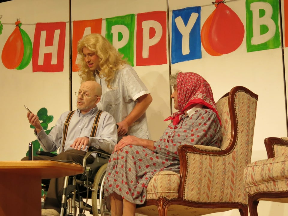 Alter Mann im Rollstuhl sitzt neben einer alten Frau mit Kopftuch.