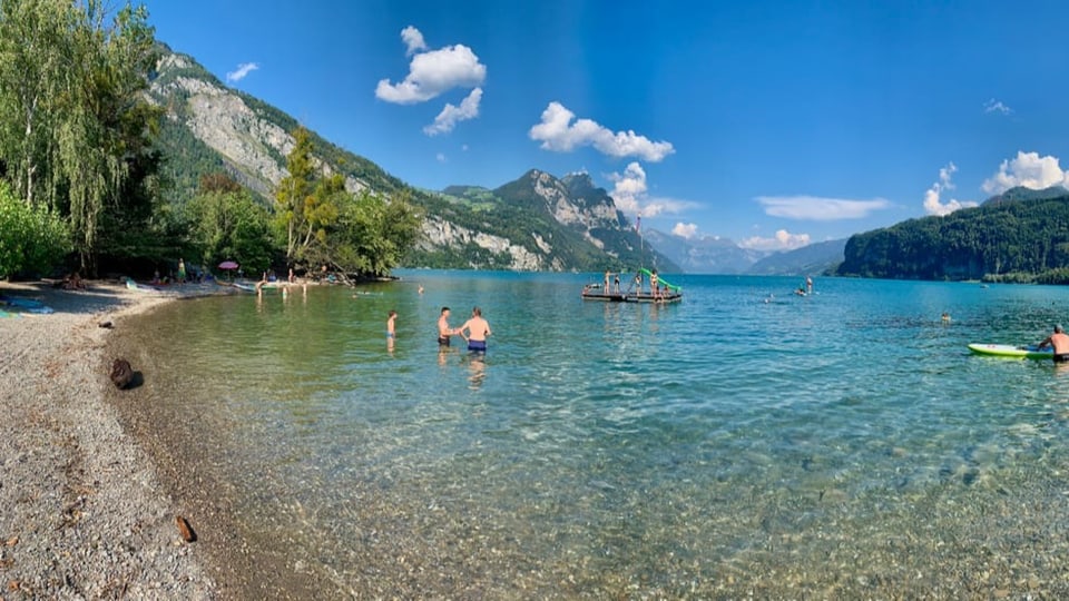 Leute Baden im See bei  viel blauem Himmel.