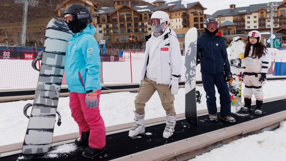 Wintersportler auf einem Teppichlift im Schnee.