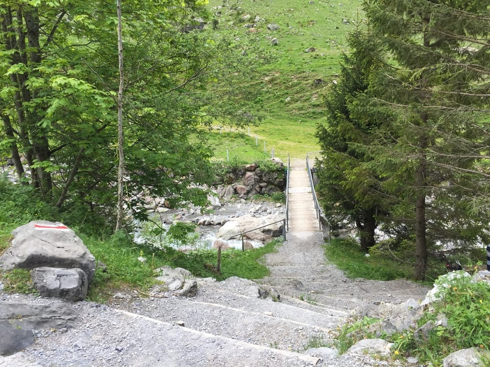 Steile Treppenstufen führen hinunter zu einer Brücke über den Bach.