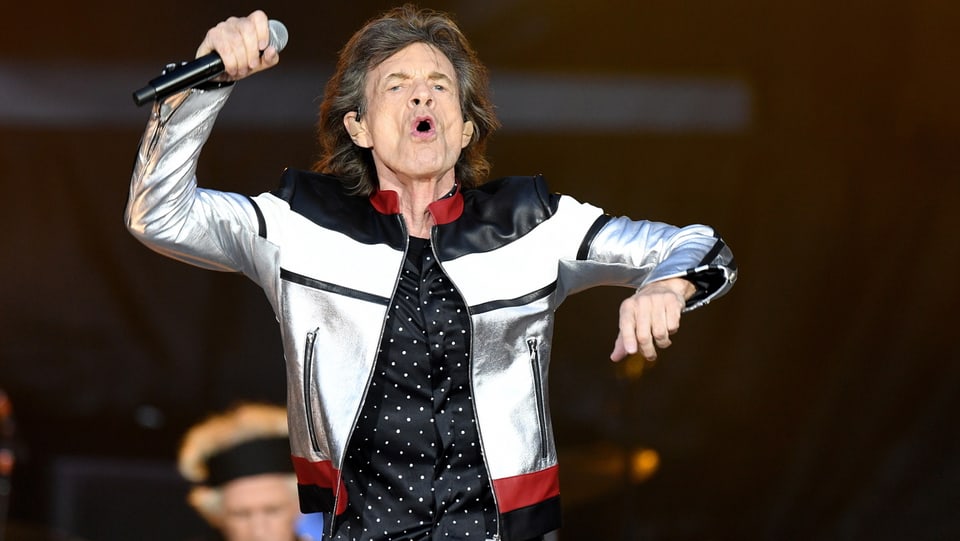 Mick Jagger in einem glitzernden Jäckchen auf der Bühne. 