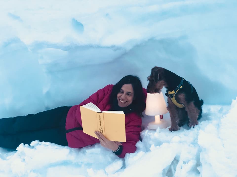 Annette König liegt im Schnee und liest den Roman «Mädchen, Frau etc.» von Bernardine Evaristo
