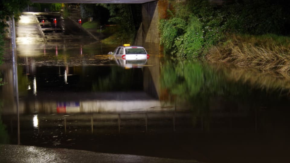 Hochwasser. Ein Taxi steht bis unters Dach im Wasser.