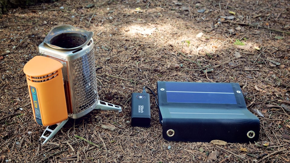 Camp Stove und Solar-Panel liegen am Waldboden.