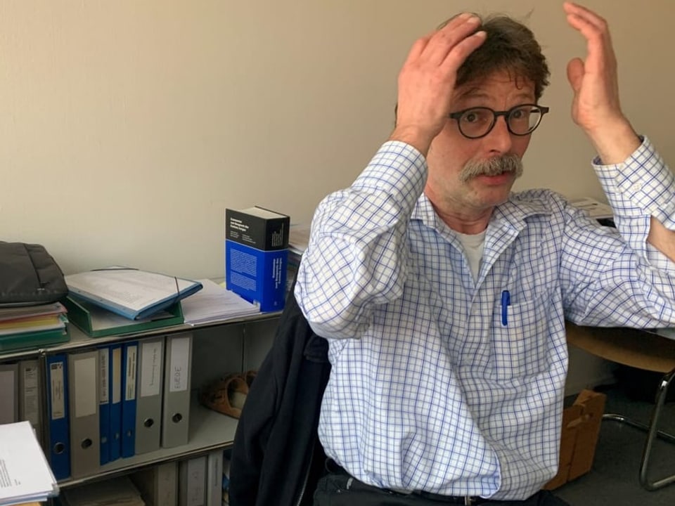 Der Kantonsbeamte Hans-Martin Plüss in seinem Büro. Er fasst sich mit den Händen an den Kopf als Geste der Enttäuschung