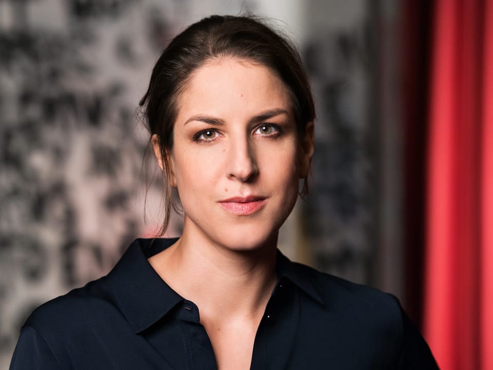 Eine junge, dunkelhaarige Frau mit einem schwarzen Oberteil.