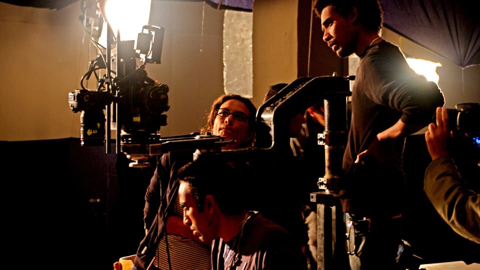 Hala Elkoussy sitzt hinter der Kamera bei einem Filmdreh, neben ihr sind zwei Mitarbeiter, die konzentriert bei der Arbeit sind.