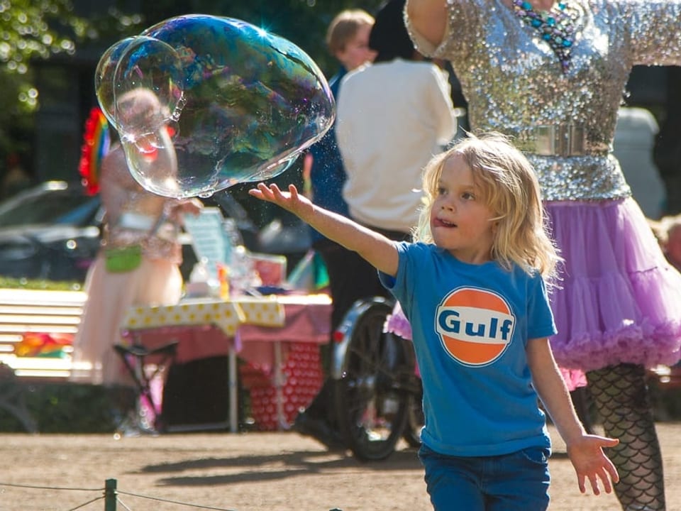 Ein Kind spielt mit einer riesigen Seifenblase.