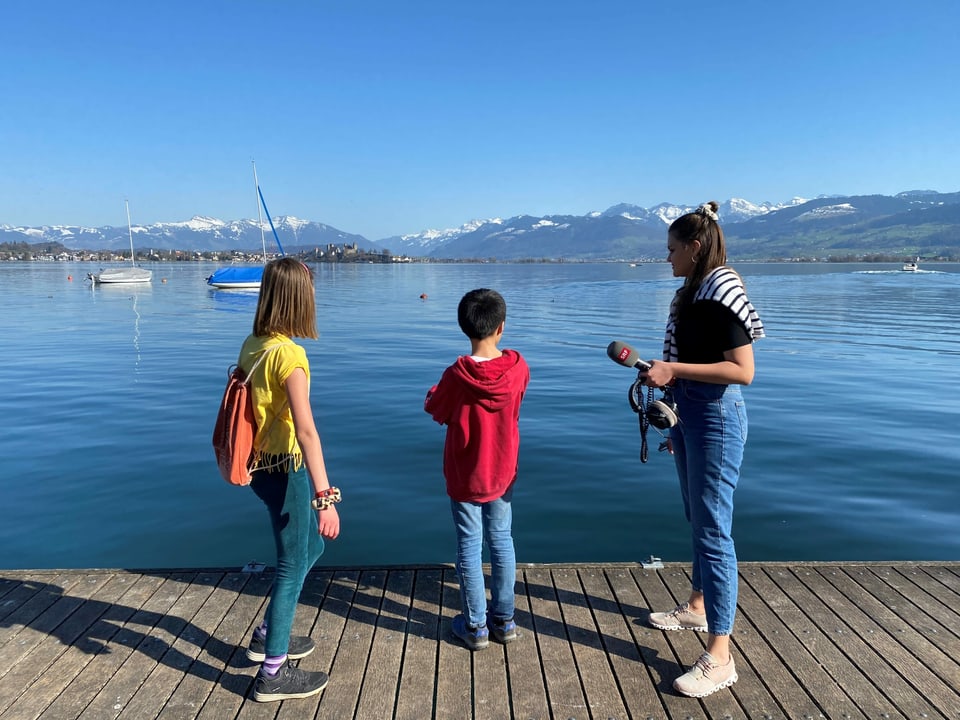 Ylva, Patrick und Angela stehen auf einem Steg und blicken auf den Zürichsee.