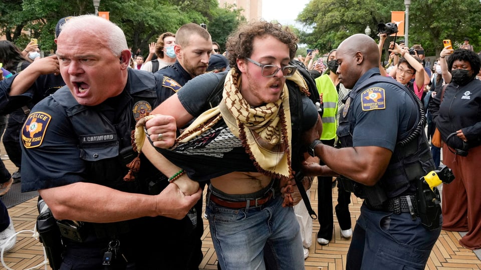Polizisten verhaften einen Demonstranten während einer öffentlichen Versammlung.