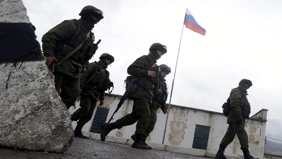 Uniformierte vor einem Armeegebäude mit der russischen Flagge.