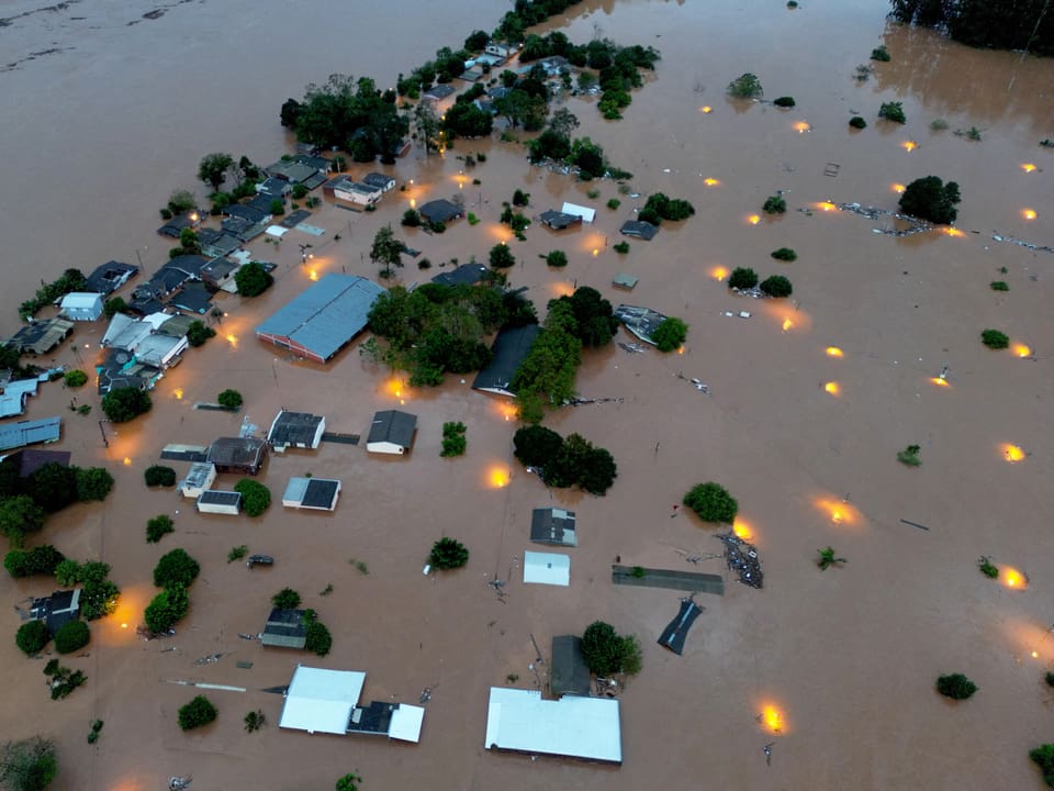 Luftaufnahme einer überschwemmten Stadt mit Strassenlaternenlichtern im Wasser.