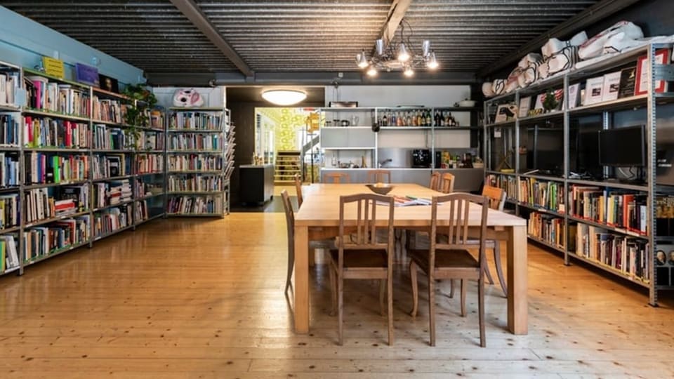 Ein Holztisch mit 8 Stühlen in einem Raum mit hunderten Büchern.