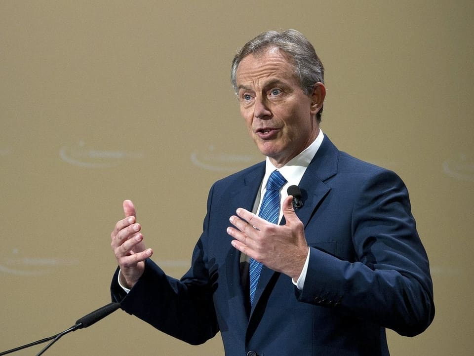 Tony Blair steht auf einer Bühne und spricht in ein Mikrofon.
