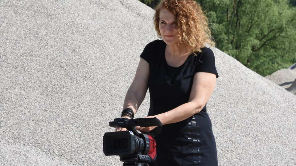 Frau mit hellen lockigen Haaren bedient eine Filmkamera