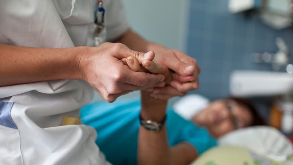 Ein Arzt untersucht die Hand einer Patientin.