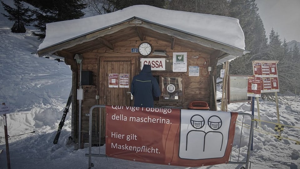Kassenhaus an der Ski-Piste mit Wanrhinweis zu Maskentragepflicht. 