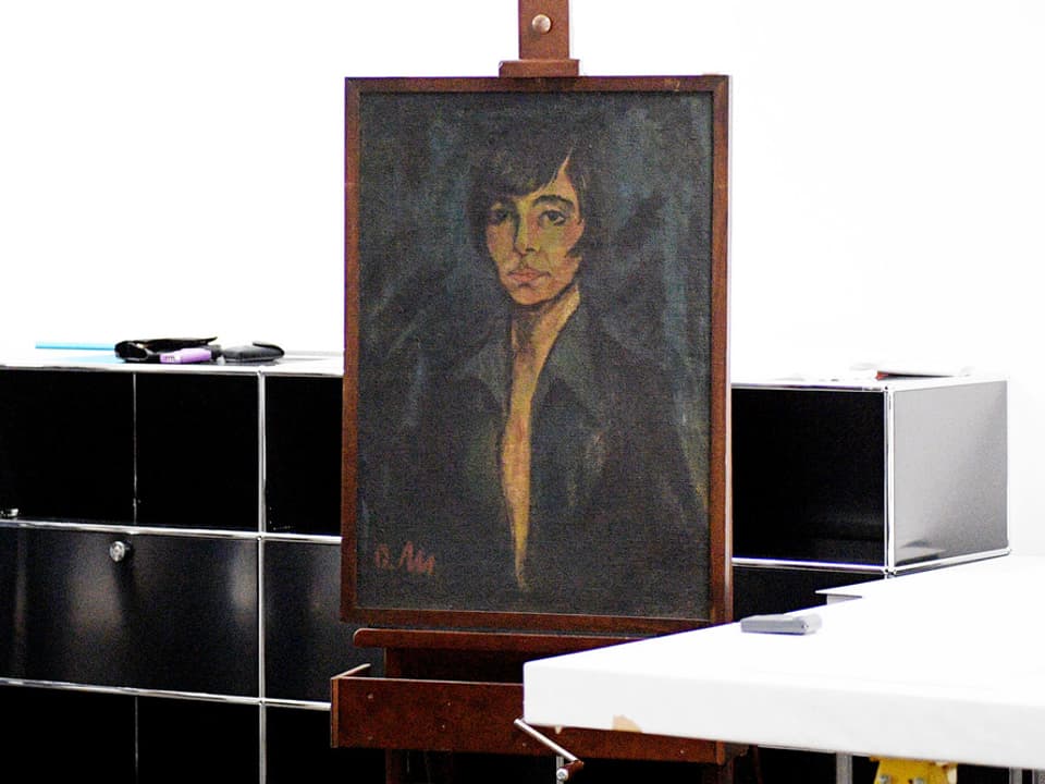 Das Gemälde eines jungen Mannes mit dunklem Haar. Das Bild steht gerahmt in einem Büroraum.