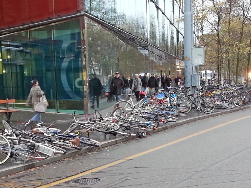 Auf dem Gehweg sind Fahrräder aufgereit. Der Wind hat viele Fahrräder durch den Dominoeffekt umgeworfen.