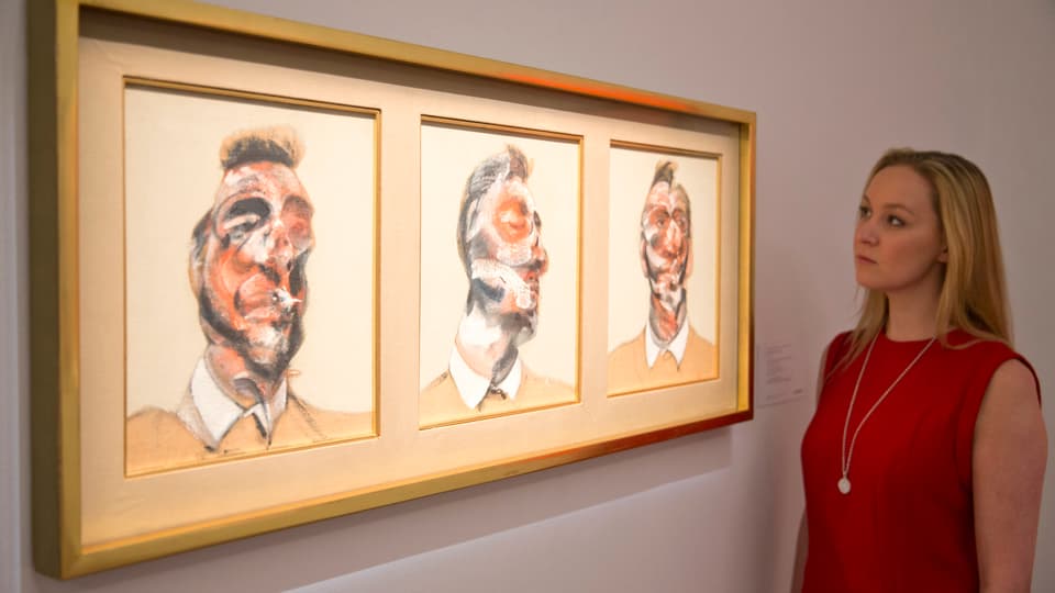 Frau steht vor dem dreigeteilten Gemälde von Francis Bacon