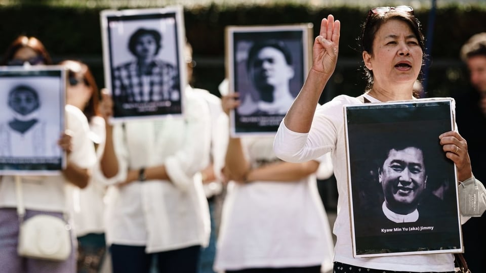 Menschen mit Fotos von verhafteten Oppositionellen vor der Botschaft Myanmars in Berlin.