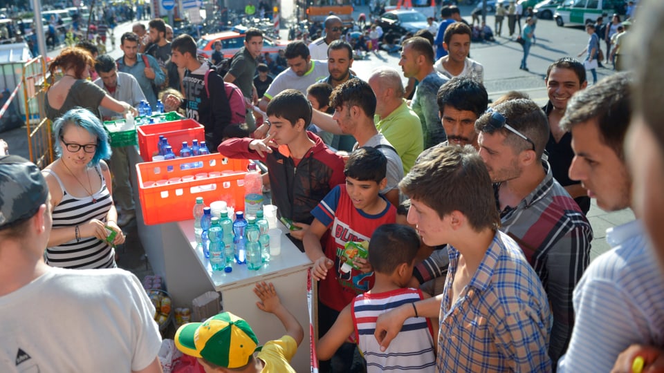 Helfer verteilen vor Bahnhof Wasser an Flüchtlinge. 