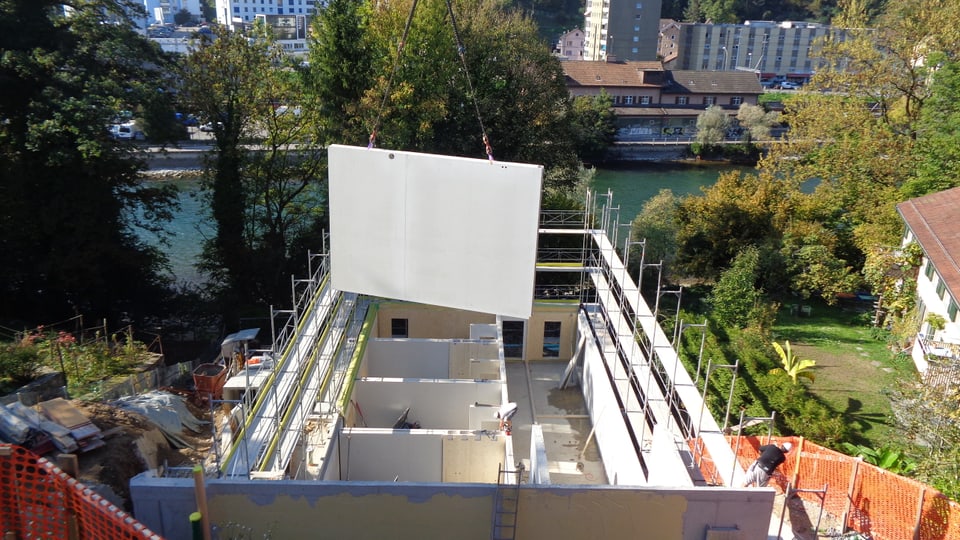 Ein Kran fügt eine Holzwand in das neue Gebäude für Musikstudenten in Luzern ein.