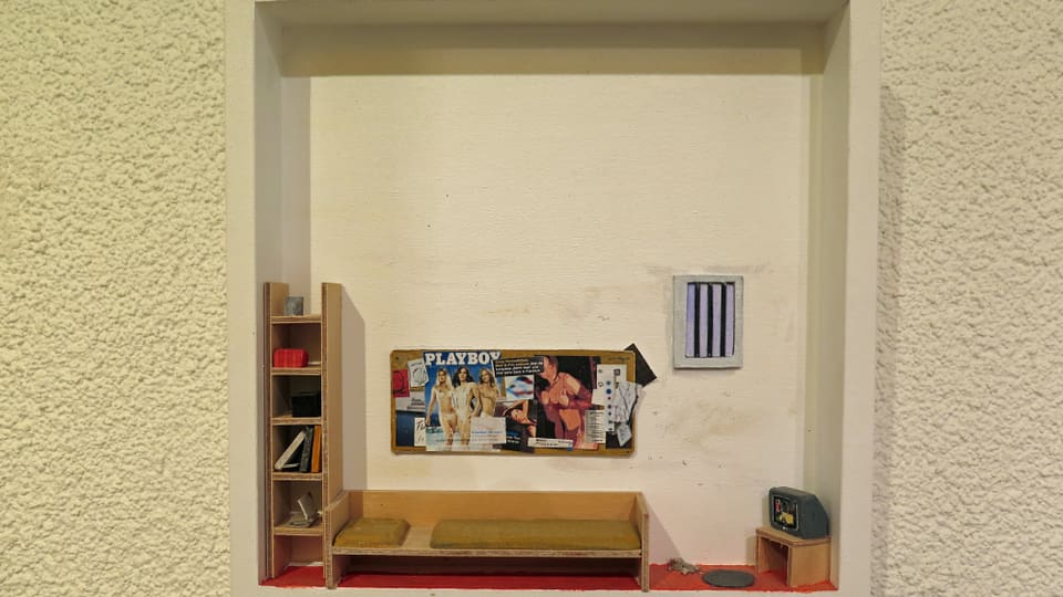 Miniaturmodell einer Gefängniszelle mit Playboy-Bildern an der Wand.