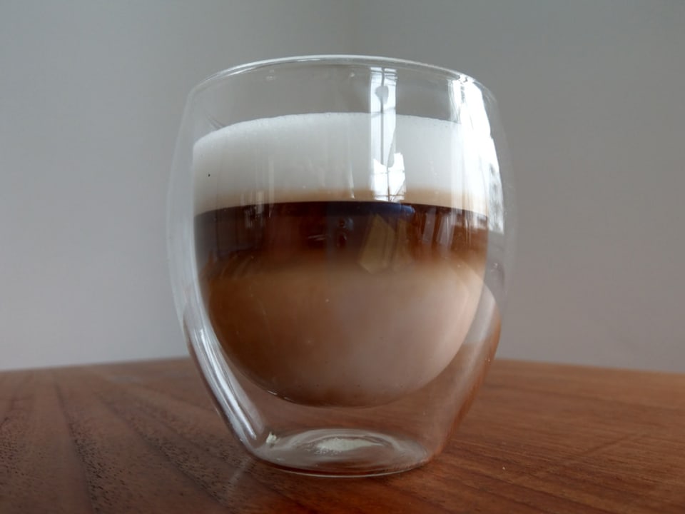 Cappuccino im Glas mit viel Milchschaum.